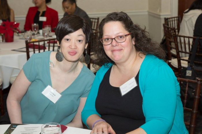 Two women pose at a table