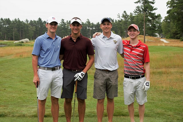 4 young men, golf gloves on, standing side by side