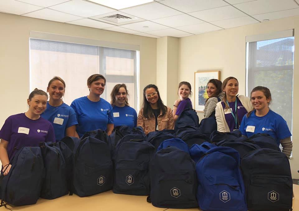 Mass General Hospital students posing in front of backpacks they filled with essential daily items to pass out to clients